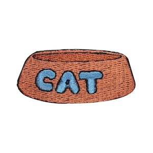 May include: A brown fabric cat food bowl with the word "CAT" embroidered in blue.