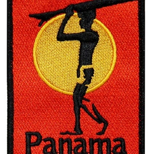 May include: A red and black embroidered patch with a silhouette of a person holding a surfboard in front of a yellow sun. The text "Panama" is below the silhouette.