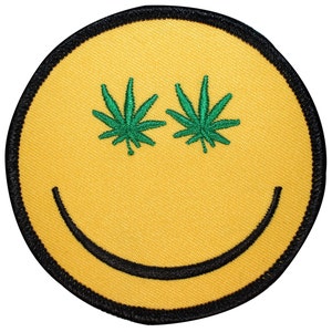 May include: Yellow smiley face patch with green marijuana leaf eyes. The patch has a black outline and a black stitched smile.