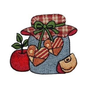 May include: A blue and white jar with a red and white checkered lid and a green bow. Two red and brown hearts hang from the lid. A red apple with a green stem and leaf is on the left side of the jar. A brown apple is on the right side of the jar.