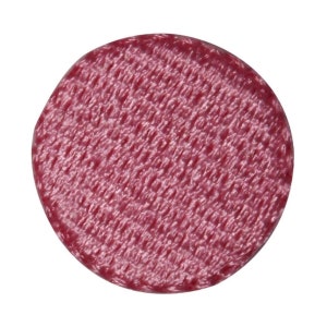 Peut inclure: Un bouton rond rose avec une surface texturée.