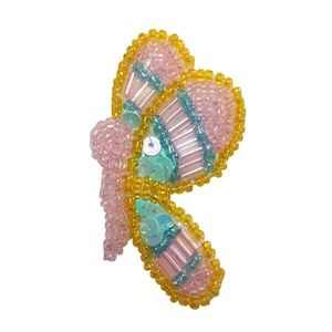 Può includere: Un'applicazione a forma di farfalla in perline rosa e gialle con paillettes turchesi. La farfalla ha un design dettagliato con perline iridescenti.