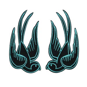 May include: Two black embroidered swallow birds with turquoise outlines, facing opposite directions.