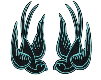May include: Two black embroidered swallow birds with turquoise outlines, facing opposite directions.