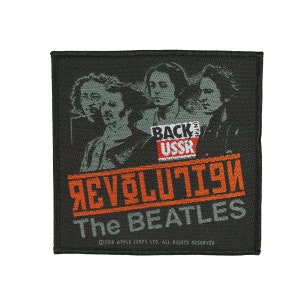 Peut inclure: Un écusson brodé noir et orange avec une photo des Beatles avec le texte "Revolution" et "The Beatles" en orange et "Back USSR" en rouge.