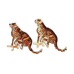 May include: Two embroidered cheetah patches in brown, black, and white. The cheetahs are sitting with their heads turned to the side.