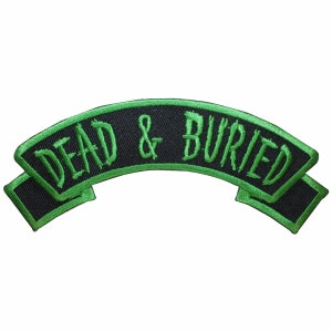 Könnte beinhalten: Grüner gestickter Aufnäher mit dem Text "DEAD & BURIED" auf schwarzem Hintergrund.