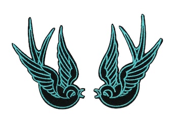 May include: Two black embroidered swallows facing each other with turquoise outlines. The swallows are in a flying position with their wings spread out.
