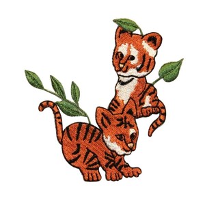May include: Two orange and black embroidered tiger cubs with green leaves. The cubs are facing different directions. The larger cub is on top of the smaller cub.