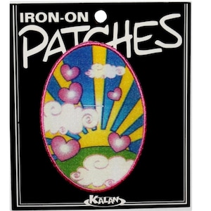 May include: An oval-shaped iron-on patch with a colorful design of a sunrise, clouds, and hearts. The patch is pink, blue, yellow, and green. The text "IRON-ON PATCHES" is printed on the card.