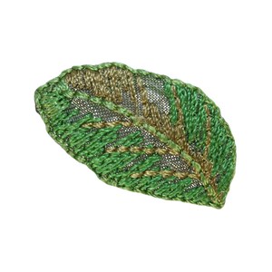 May include: A green and gold embroidered leaf with a detailed design. The leaf is made of fabric and has a textured surface.
