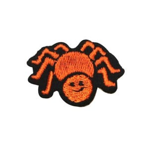 May include: Orange embroidered spider with a smiling face, black outline, iron-on patch.