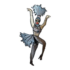 May include: An embroidered iron-on patch of a dancer wearing a blue and white feathered costume, black pants, and black shoes. The dancer has red lips and is posed with arms raised.
