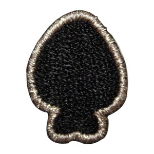 Può includere: Una toppa ricamata nera a forma di punta di lancia con un contorno beige.