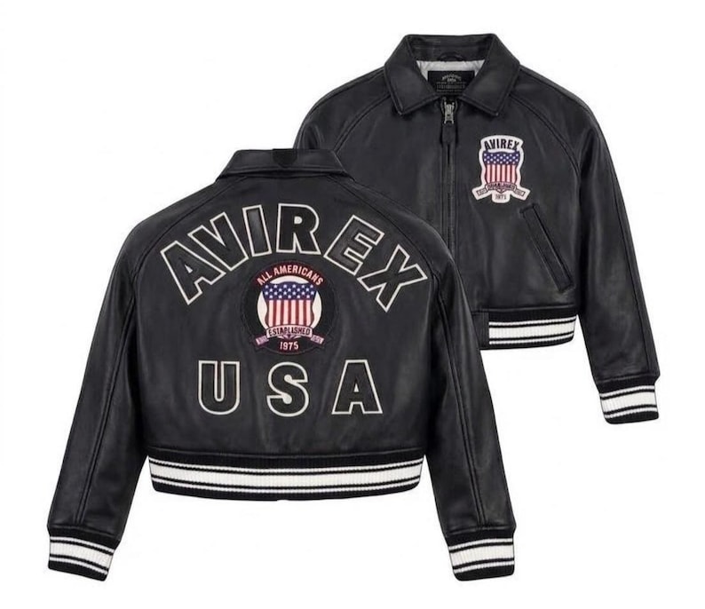 May include: A black leather jacket featuring a front zipper, a collar, and striped ribbed cuffs and hem. The back displays the text AVIREX USA and a circular patch with an American flag and the text ALL AMERICANS ESTABLISHED 1975.