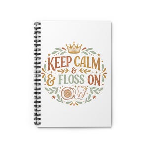 Könnte beinhalten: Ein weißes Spiralnotizbuch mit einer zentralen Grafik und dem Text KEEP CALM & FLOSS ON. Das Design zeigt eine Krone, einen Zahn und einen Zahnseide-Spender, umgeben von dekorativen Blättern und Sternen in gedeckten Orange- und Grüntönen.