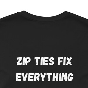 May include: Black crew neck t-shirt with the white text "ZIP TIES FIX EVERYTHING" in a bold, distressed font. The shirt is made of a soft material and is suitable for casual wear.