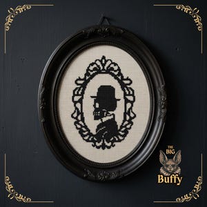 May include: A black and white cross-stitch embroidery featuring a silhouette of a skull wearing a bowler hat, enclosed in an ornate oval frame. The design is set within a black oval frame. The text THE BIG Buffy is visible in the bottom right.