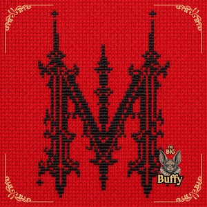 May include: A cross-stitch pattern on a bright red fabric background featuring a large, ornate black letter M in the centre. In the bottom right corner, there is a small illustration of a bat with the text THE BIG Buffy printed below it.