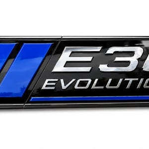 Könnte beinhalten: Ein rechteckiges Emblem mit schwarzem Hintergrund und zwei vertikalen blauen Streifen auf der linken Seite. Der Text E30 ist in großen, metallisch silbernen Buchstaben über dem Wort EVOLUTION in kleinerer Schrift dargestellt, schwarz umrandet.