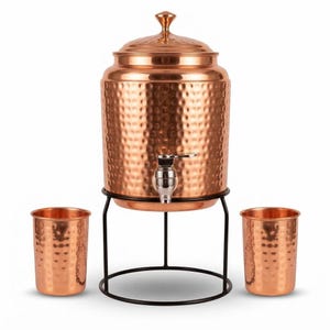 May include: A hammered copper water dispenser with a lid and a silver-toned metal spigot, resting on a black metal stand. Two matching hammered copper tumblers are positioned on either side of the stand, completing this beverage set.