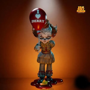Op de afbeelding: Een beeldje van Pennywise de clown, met een rode ballon met "I ❤️ DERRY". Het figuur draagt een vintage clownskostuum met een gerimpelde kraag en een sinistere uitdrukking. Een papieren boot ligt in een plas rode vloeistof.