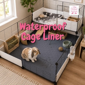 May include: A multi-level wire pet cage featuring a dark gray waterproof cage liner with a quilted pattern. The enclosure includes a brown and white rabbit, a wooden hay feeder, a water bottle, a bowl, and a loft area with a star-patterned mat.