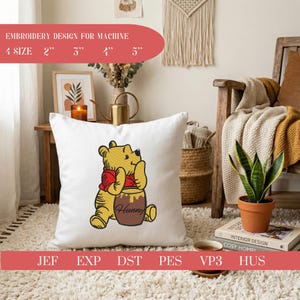 May include: A white square throw pillow featuring an embroidered yellow bear wearing a red shirt, sitting and holding a brown honey pot with the word Hunny written on it. The design is for machine embroidery in 2, 3, 4, and 5 inch sizes.