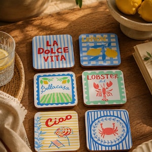Pode incluir: Um conjunto de seis porta-copos quadrados com várias ilustrações e texto. Os designs incluem riscas azuis com 'LA DOLCE VITA', um padrão axadrezado azul com limões, 'Bellacasa' com uma paisagem, 'LOBSTER club' com uma lagosta, 'Ciao' com um guarda-sol e um caranguejo.