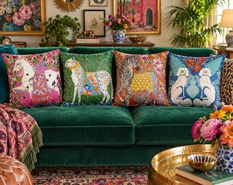 May include: Four square throw cushions arranged on a green sofa. The first features a white horse on a pink background, the second a cheetah on green, the third a zebra on orange, and the fourth two white dogs on a blue background with floral motifs.