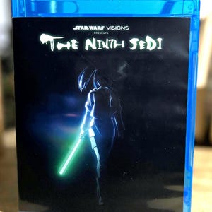 Könnte beinhalten: Eine blaue Blu-ray-Hülle mit dem Cover von Star Wars Visions Presents The Ninth Jedi. Das schwarze Cover zeigt die Silhouette einer Figur, die ein leuchtend grünes Lichtschwert hält, mit dem Titeltext in Weiß oben in der Mitte.