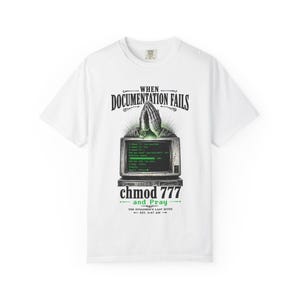 May include: A white t-shirt featuring a graphic of praying hands above a computer monitor displaying green terminal text. The text reads: WHEN DOCUMENTATION FAILS, chmod 777 and Pray, THE SYSADMIN'S LAST RITES, EST. 3:47 AM. The design uses black and green ink.