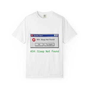 Könnte beinhalten: Weißes T-Shirt mit einer Grafik einer Computerfehlermeldung. Die Meldung lautet "System Alert" und "404: Sleep Not Found". Unter der Grafik steht der Text "404: Sleep Not Found" in Grün.