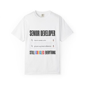 May include: A white short-sleeve t-shirt featuring the black text SENIOR DEVELOPER, two search bar graphics with the text how to center a div and git pull vs git fetch difference, and the text STILL GOOGLES EVERYTHING with a multicolored logo.