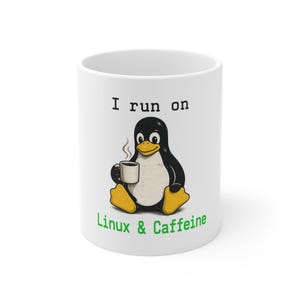 May include: White ceramic coffee mug with a cartoon penguin illustration. The penguin is black and white with yellow feet, holding a coffee cup. Text on the mug reads "I run on Linux & Caffeine."