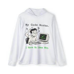 May include: White long-sleeved hoodie featuring a cartoon graphic of a person looking confused in front of a computer screen. The screen shows "SUCCESS." Text reads "My Code Works. I Have No Idea Why."