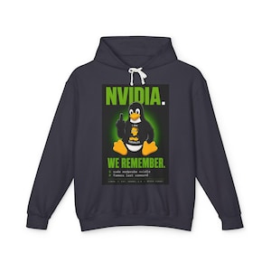 Puede incluir: Una sudadera con capucha gris carbón oscuro con un estampado gráfico de un pingüino con pies y pico naranjas, que lleva una camiseta con la inscripción I AM TORVALDS. El texto dice NVIDIA. WE REMEMBER. con líneas de código sudo modprobe.