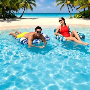 May include: Two inflatable pool floats with a blue and white tropical leaf pattern. One float is rectangular and supports a person in yellow swim trunks, while the other is a chair-style float supporting a person in a red one-piece swimsuit.