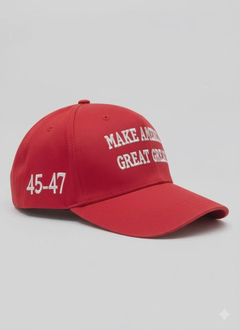 May include: A red baseball cap featuring white embroidered text on the front that reads MAKE AMERICA GREAT AGAIN and the numbers 45-47 embroidered in white on the side. The cap has a structured crown, a curved brim, and a button on the top center.