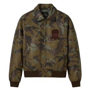 May include: A camouflage leather jacket in green, brown, and tan. The jacket has a collared neckline, a zip closure, and a brown ribbed hem and cuffs. A brown patch is sewn on the chest. The brand name "AVIREX" is visible on the collar.