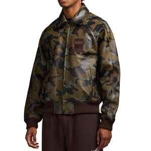 May include: A camouflage jacket in green, brown, and black. The jacket has a collared neckline, a front zip, and brown ribbed hem and cuffs. A patch with text is visible on the chest. The jacket appears to be made of a leather-like material.