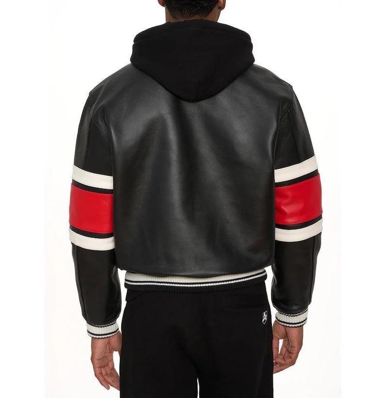 May include: Black leather jacket with a black hood, red and white striped sleeves, and a white and black striped hem. The jacket is worn with black pants. The back view of the jacket is shown.