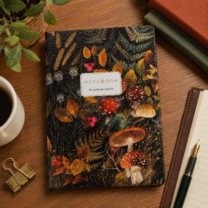 Puede incluir: Un cuaderno rectangular con una cubierta oscura y texturizada que presenta una ilustración botánica de helechos, hojas de otoño, bayas rojas y varios hongos. Una etiqueta blanca central muestra el texto NOTEBOOK BV by Bruno Visconti.