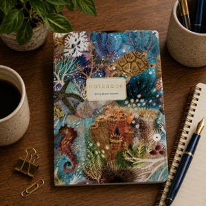 May include: A notebook with a colorful underwater scene featuring a sea turtle, seahorse, starfish, and coral reef. The cover has a central rectangular label with the text NOTEBOOK and BV by Bruno Visconti printed in gold lettering.