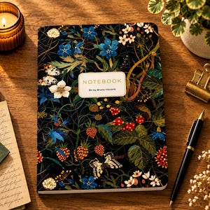May include: A rectangular notebook with a black cover featuring a botanical print of blue flowers, red strawberries, green leaves, and butterflies. A white rectangular label in the center displays the text NOTEBOOK and BV by Bruno Visconti.