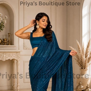 Puede incluir: Un sari de color azul cerceta profundo con una blusa sin mangas de cuello cuadrado. La tela está adornada con lentejuelas brillantes en toda su superficie, y el borde inferior presenta un patrón curvo de lentejuelas doradas sobre la base.