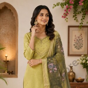 May include: A light green salwar kameez suit with a matching dupatta. The suit has embroidery on the neckline and sleeves. The dupatta features a floral print with green and pink hues.