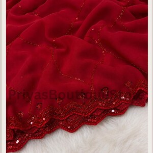 May include: A deep red fabric featuring a delicate, flowing drape with a scalloped edge. The material is adorned with intricate, thin lines of matching red sequins arranged in a diamond pattern, with additional sequin detailing along the border.