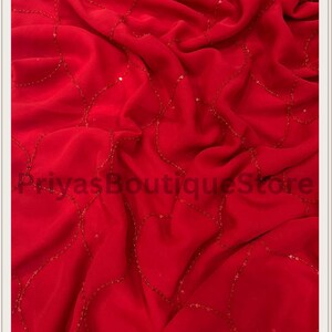 May include: A vibrant red fabric featuring a delicate, flowing pattern of interconnected, curved lines embellished with small, shimmering red sequins. The material is draped in soft folds, and the text PriyasBoutiqueStore is visible.