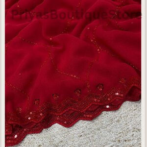 May include: A deep red fabric featuring a scalloped edge with intricate red sequin embroidery. The material is draped in soft folds, and the surface is decorated with delicate, curved lines of matching red sequins. The text PriyasBoutiqueStore is visible.